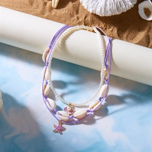 Detail der böhmischen Seestern- und Muschelhalskette mit Perlen auf Strandsand
