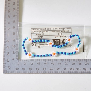 Macro-opname van een handgemaakte boho kralen enkelband met bloemen in blauw en wit