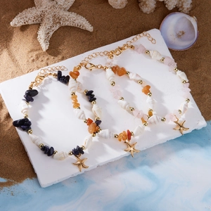 Detailaufnahme der Seestern- und Muschelarmbänder mit Natursteinen auf Strandsand