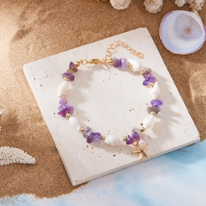 Detail eines Boho-Strandarmbands mit lila Kies, Muscheln und einem goldenen Seestern