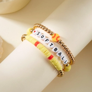 Detail van softball meerlagige armbandset met gele heishi-kralen en gouden bedeltjes