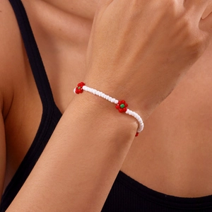 Detail van de handgemaakte witte kralen enkelband met rode en groene bloemmotieven