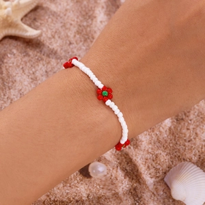 Detailopname van handgemaakte boho-enkelband met kralenbloemen op een zandstrand decor
