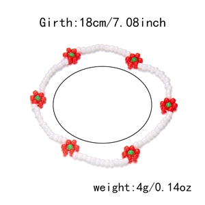 Detail van handgemaakte bohemian enkelband met witte kralen en rood-groene bloemen