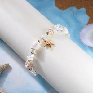 Detail eines Strandarmbands mit Muscheln, Kristallen und goldenem Seestern-Anhänger