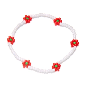 Detail van handgemaakte bohemien enkelband met witte kralen en rode bloemmotieven