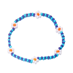Detail van een handgemaakte kralen enkelband met blauwe kralen en witte bloemen