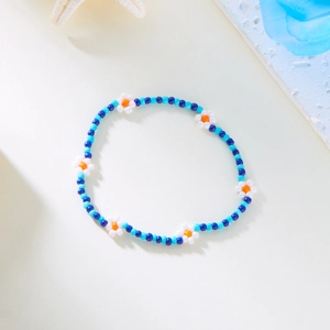 Detailopname van handgemaakte Bohemian enkelband met blauwe en witte bloemkralen