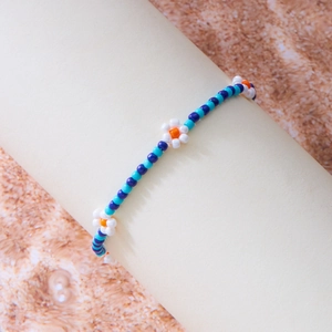 Detail van handgemaakte bohemien enkelband met blauwe en witte kralen en bloemen