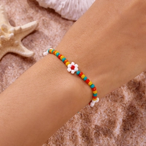 Detail van handgemaakte kleurrijke kralen enkelband met bloem op een zandstrand