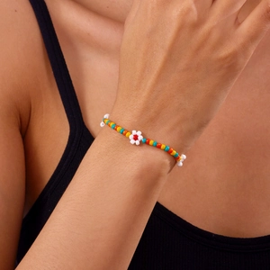 Detail van handgemaakte kleurrijke kralenarmband met bloemaccent om de pols gedragen