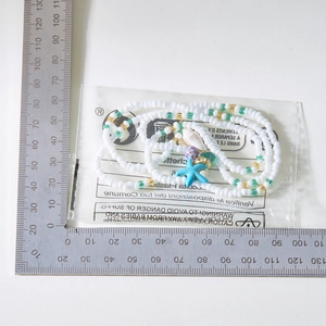 Detail von Perlenfußkettchen mit bunten Seesternen und Muschelanhängern in Verpackung