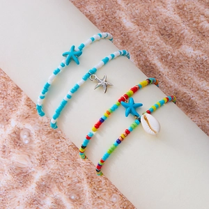 Detail von 4er-Set Boho-Fußkettchen mit Seestern und Muschel auf Sandhintergrund