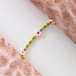 Detail van handgemaakte boho enkelband met kleurrijke kralen en madeliefjesbloemen