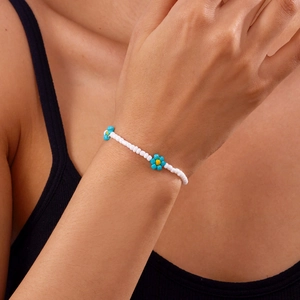 Detail van een handgemaakte enkelband van kralen met blauwe en gele bloemen