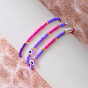 Nahaufnahme von Boho-Perlenarmbändern mit Evil-Eye-Anhängern und goldenen Details im 3er-Set