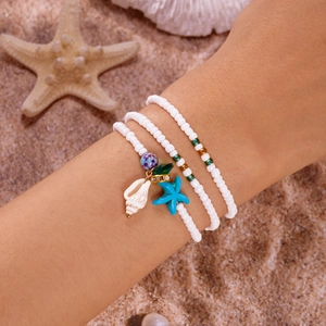 Details des böhmischen Lagen-Perlenarmbands mit Muschel- und Seestern-Anhängern am Strand