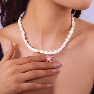 Detail view of a shell necklace featuring a pink starfish charm on a model's neck