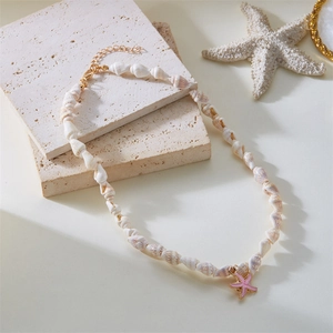 Ocean style necklace with shell beads and starfish pendant on a white stone surface