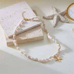 Detail of natural conch shell beaded necklace featuring a gold starfish pendant charm