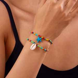 Detail von bunten böhmischen Perlenarmbändern mit Seestern- und Muschelanhängern
