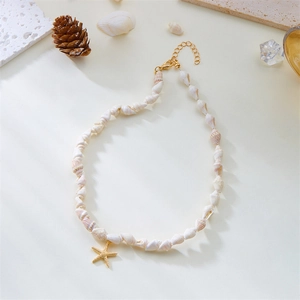 Detail of white spiral seashell necklace with a textured golden starfish pendant on top