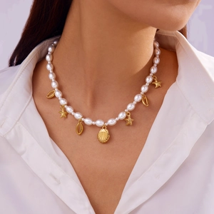 Detail of seashell and starfish charms on a white pearl necklace worn as a choker