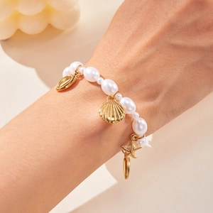 Detail of seashell beach bracelet with white pearls and gold starfish sea snail charms