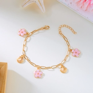 Detailansicht der goldenen Fußkette mit rosa Emailleblumen und Muschelanhängern am Strand