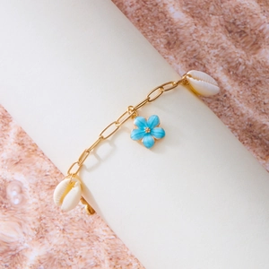 Detail der goldenen Muschel-Fußkette mit Kaurischnecken und hellblauer Emaille-Blume