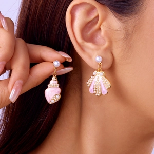 Detail eines rosa Muschelohrrings mit kleinen Perlen und Goldrand am Modell getragen