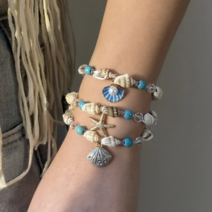 Detail von Boho-Ozean-Armbändern mit Seestern- und Muschelanhängern am Handgelenk