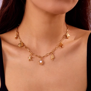Close-up of golden nautical necklace with sea stars, pearls and turtle charms on a model