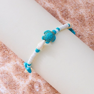 Detailaufnahme einer Strand-Fußkette mit Türkis-Schildkröte und echten Naturmuscheln