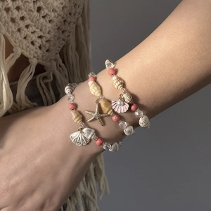 Detailansicht von Boho-Perlenarmbändern mit Muscheln und Seesternen am Handgelenk
