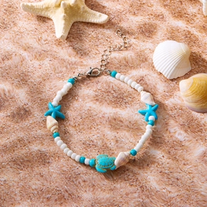 Detailansicht eines Strand-Fußkettchens mit blauem Seestern, Schildkröte und Muscheln