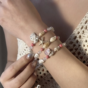 Detail eines mehrlagigen Ozean-Perlenarmbands mit Seestern- und Muschelanhängern