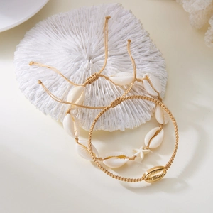 Detail of bohemian starfish and cowrie shell beaded anklets on white coral stand