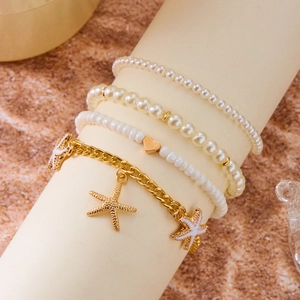 Detail of bohemian gold starfish charms and white faux pearl layered anklet set