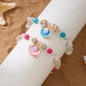 Detail von Strandarmbändern mit blauen und rosa Muschel-Anhängern auf weißem Ständer