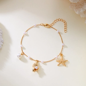 Close-up of bohemian gold starfish and seashell charms on a beaded layered anklet