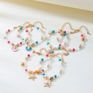 Detailansicht von sechs böhmischen Perlenarmbändern mit Muscheln und goldenen Anhängern