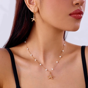 Detailansicht einer goldenen Seesternkette mit Perlen am Model für den Strand-Sommerstil