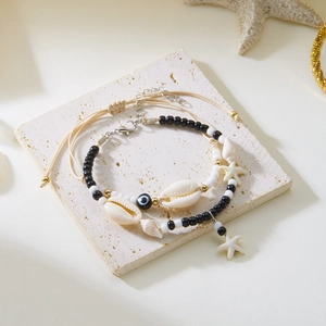 Detail of bohemian layered anklet with starfish, shells, and blue evil eye beads