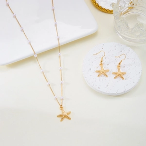 Elegantes Gold-Seestern-Halsketten und Ohrring-Set mit weißen Perlen auf Dekotablett