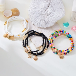Detail view of multi-layered beaded anklet set with starfish, seashell, and coin charms