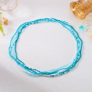 Detail of layered blue and white beaded waist chains styled with sea shells and starfish