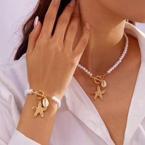 Detail von Perlenkette und Armband mit goldenem Seestern und Muschel-Anhängern