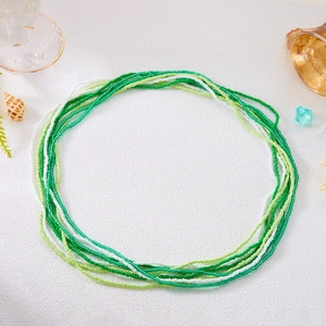 Detail shot of multi-layer green and white beaded waist chains with shells on white sand