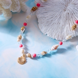 Detailaufnahme der Perlenkette mit Muscheln, roten Perlen und goldenem Muschel-Anhänger